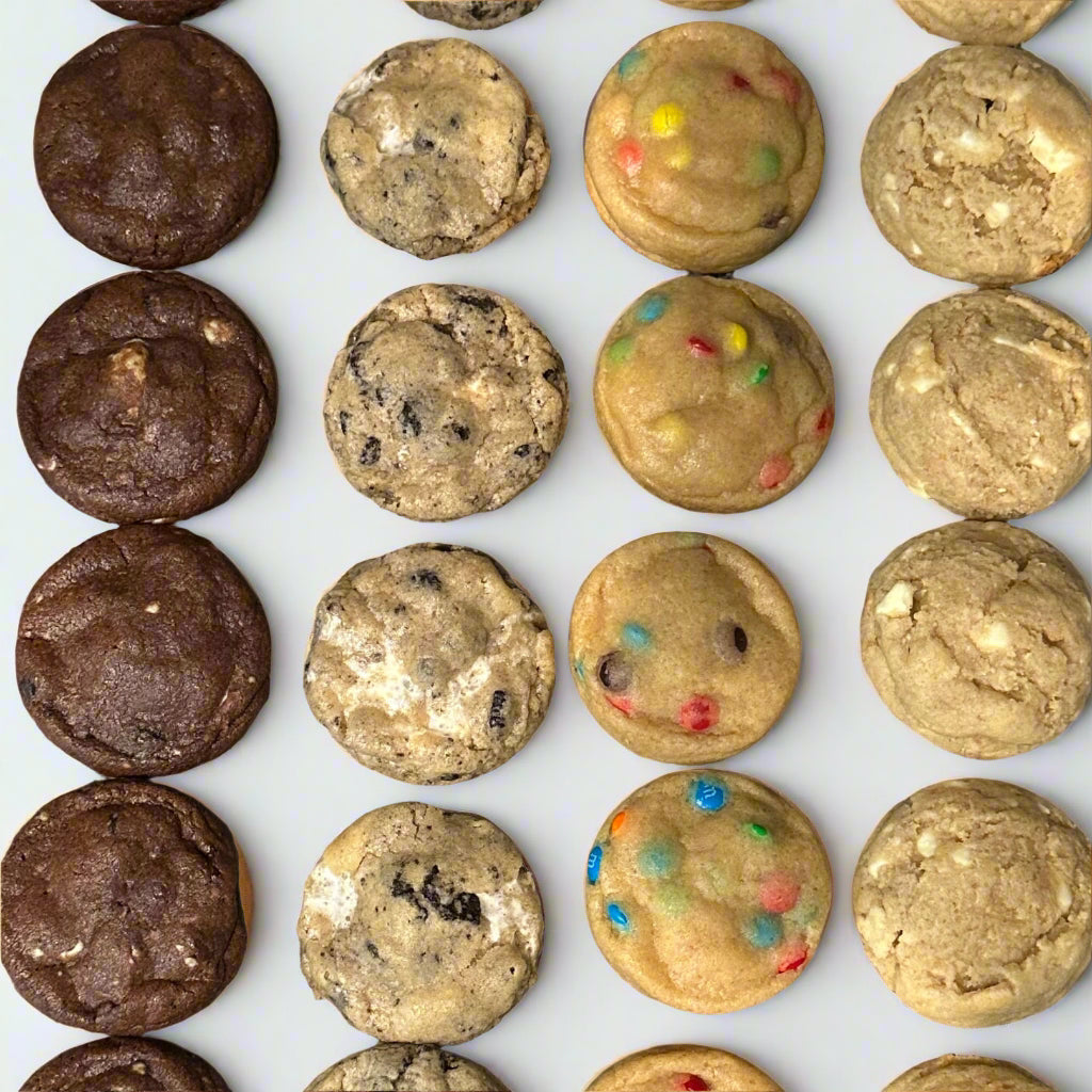 Assorted cookies including chocolate, sugar, and M&M cookies on a cooling rack.